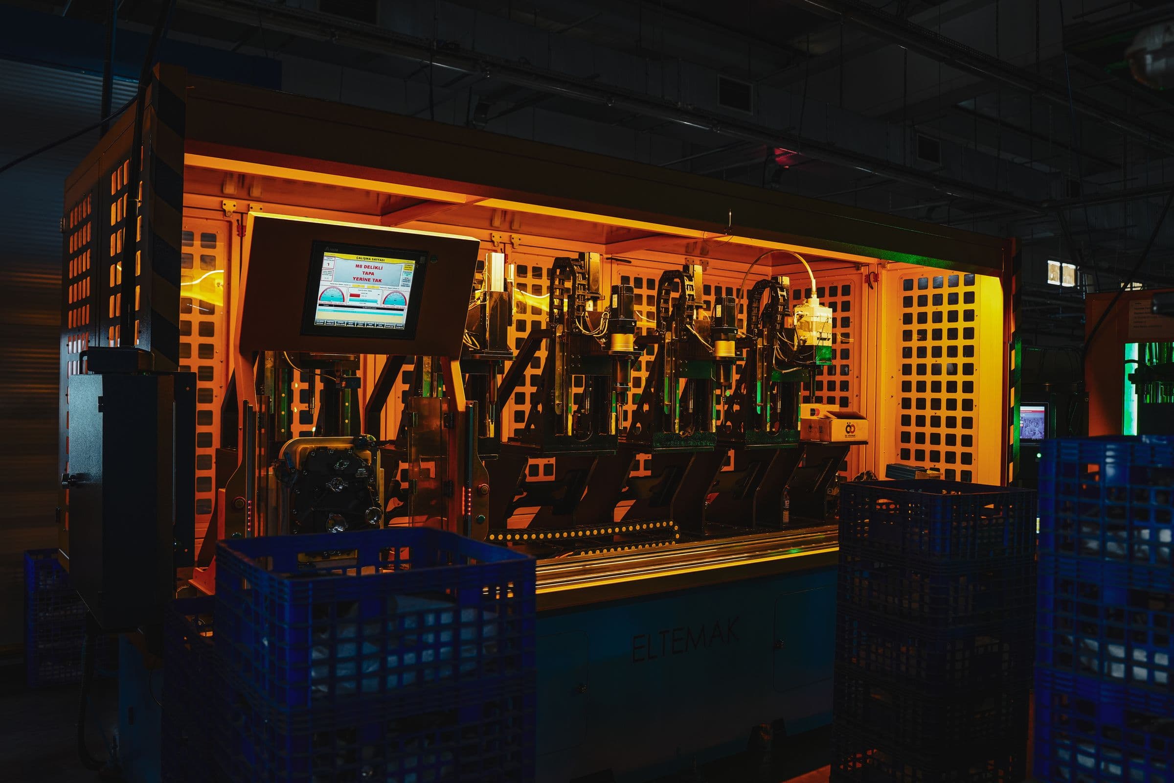 Industrial machinery under amber work lighting in a dark plant